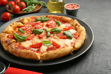 Delicious Margherita pizza and ingredients on black table