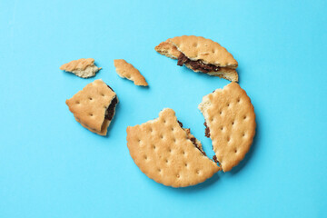 Pieces of tasty sandwich cookie on light blue background, top view