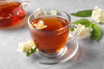 Hot jasmine tea in cup and flowers on light grey table