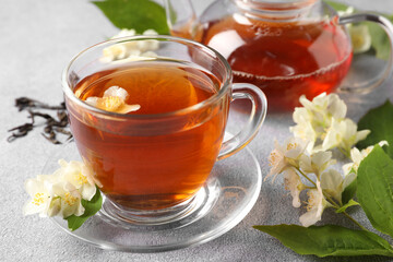 Hot jasmine tea in cup and flowers on light grey table