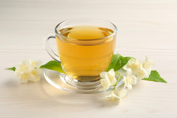 Hot jasmine tea in cup and flowers on white wooden table