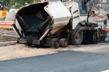 Asphalt Paver Machine Laying Down Fresh Asphalt on Construction Site During Daylight Hours