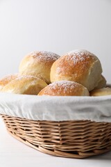 Delicious dough balls in basket on white wooden table