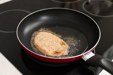 Cooking schnitzel in frying pan on stove, closeup