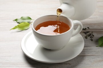 Pouring refreshing green tea into cup at grey wooden table, closeup