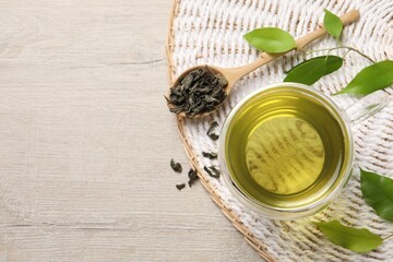 Refreshing green tea in cup, spoon and leaves on wooden table, flat lay. Space for text