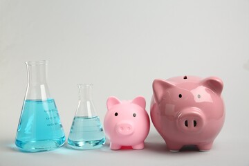 Water save concept. Piggy banks and laboratory glassware with liquid on light grey background