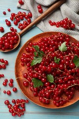 Fresh red currants and leaves on light blue wooden table, flat lay