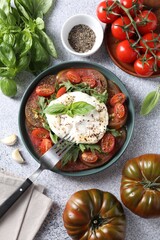Delicious fresh burrata salad in bowl served on light gray textured table, flat lay