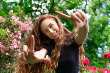 Smiling Redhead Woman Posing in Garden With Flowers in Background