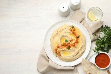 Delicious hummus with olive oil, chickpeas and paprika served on white wooden table, flat lay. Space for text