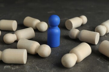 Blue piece among wooden ones on grey table, closeup