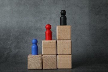 Different figures on wooden ladder against grey background
