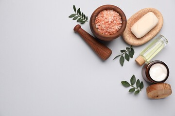 Different cosmetic products and leaves on light grey background, flat lay. Space for text