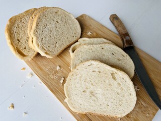 Loaf of bun. Sliced bread on a cutting board with a knife on a white background