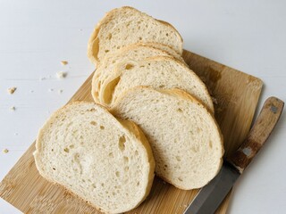Loaf of bun. Sliced bread on a cutting board with a knife on a white background