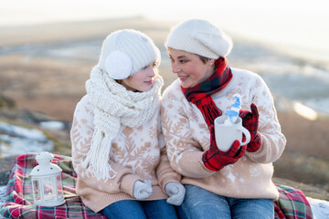 Two Women Enjoying  Winter Day With Hot Chocolate and Blanket on Hill
