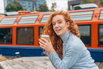 Redhead Woman Holding Coffee Cup Near Orange Boat