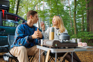 Couple Taking a Break with Marshmallows Next to Minivan Outdoors