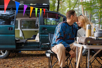 Camping Bliss: Couple Enjoying Nature's Peace by Their Camper