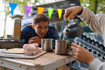 Young Couple Enjoying Tea Amidst Scenic Outdoors and Camper
