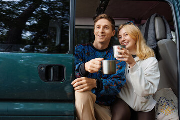 Young lovers relaxing with tea near their travel camper