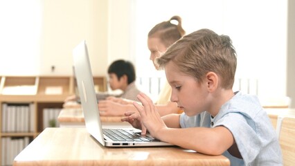 Caucasian smart child programing software system and learning about coding while multicultural searching about engineering code. Happy boy thinking about engineering prompt by using laptop. Pedagogy.