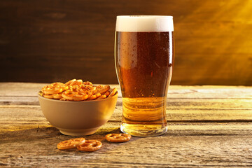 Glass of beer and pretzel crackers on wooden table