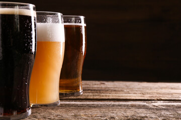 Glasses with different types of beer on wooden table, closeup. Space for text
