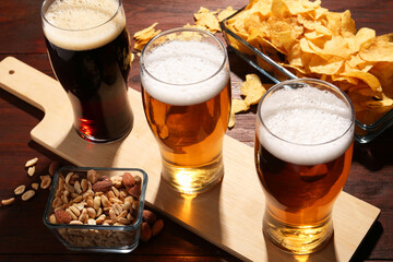 Glasses of beer and snacks on wooden table