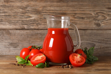 Tasty tomato juice in glass jug, fresh vegetables and spices on wooden table