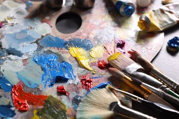 Fototapeta premium Artist's palette, brushes and paints on grey table, closeup