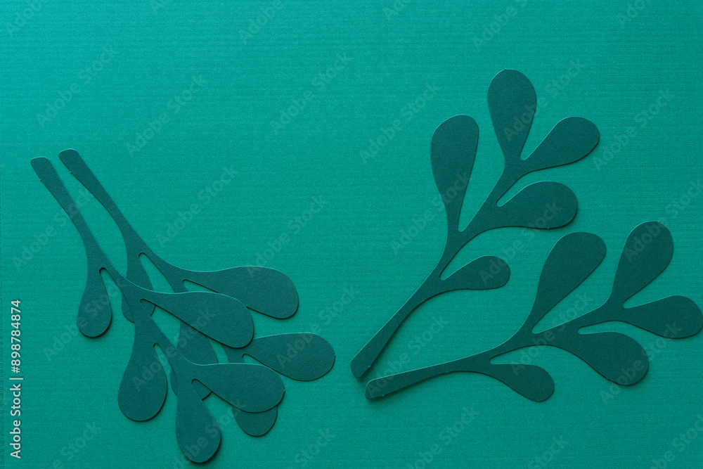 Wall mural stylized paper leaves die-cut from dark green paper on blank green paper with space for copy