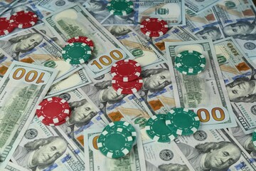 Many dollar banknotes and casino chips as background, closeup