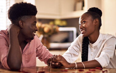 Black couple, kitchen and romance in home with love, smile and bonding together with rose petals. Happy, man and woman holding hands with trust, relax and celebrating Valentines day or anniversary