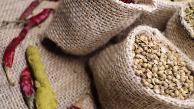 Bag of spice, dry red pepper, turmeric, cumin and coriander background. Indian cooking spices 4k footage. 
