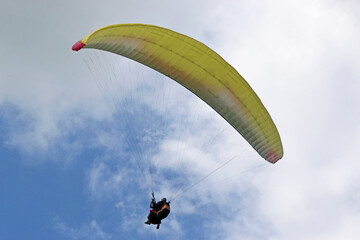 Tandem Paraglider flying in a cloudy sky	