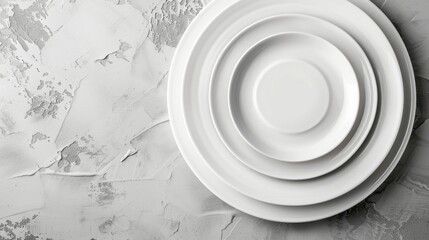 Stacked white porcelain dining plates on light gray surface for elegant table setting