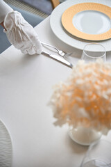 Top view of waiter hand in white glove setting a table in modern restaurant