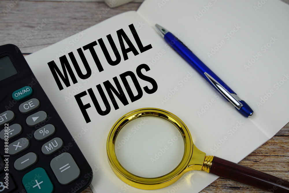 Poster mutual funds text message written on note page with calculator and magnifying glass top view on wood