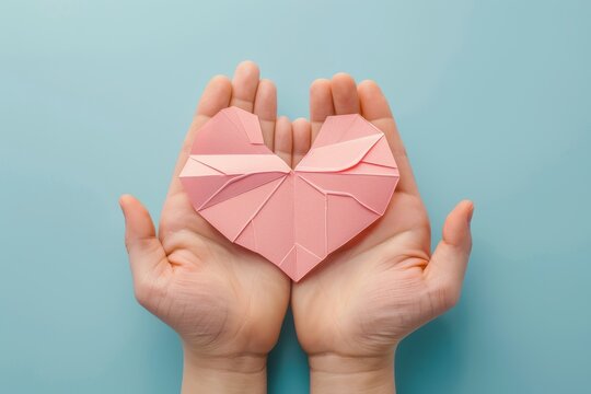 Hands holding paper liver on blue background