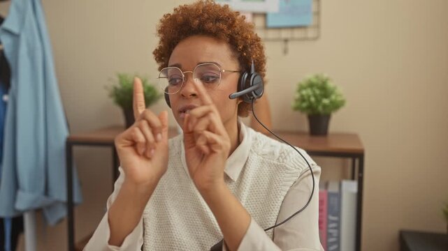 African american woman with headphones communicating in sign language in a cozy home interior.