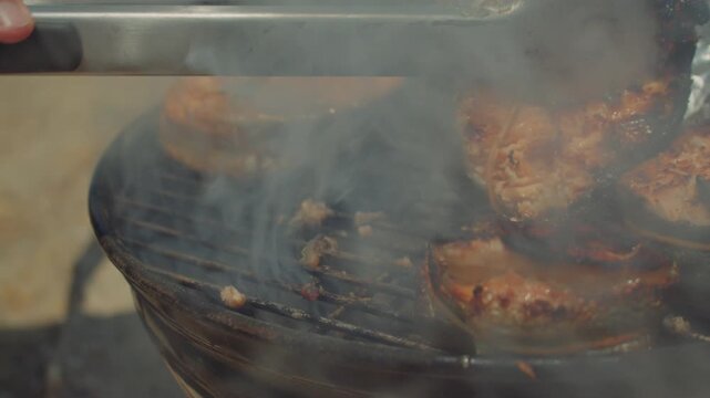 A cook turns over some salmon steaks on a roasting grate and reveals black burnt stains. Fish barbecue gone wrong, Burnt fish.