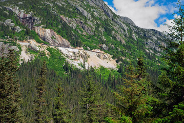 Alaskan mountain scene near Skagway with passenger train (very tiny just above center) descending...
