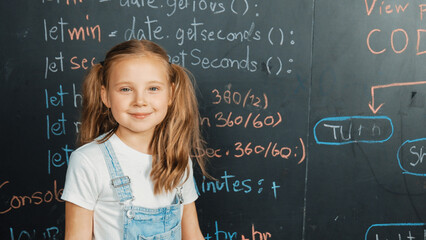 Happy caucasian girl looking at camera while standing at board with engineering prompt or coding,...