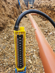 Drainage testing equipment placed next to a drainage pipe in an excavated trench. Site preparation and ground excavation concept. Design for construction, architecture, poster, banner.