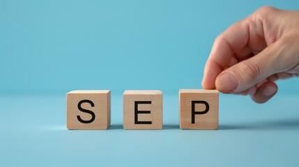 Month and date concept, hand pick the September wooden block to plain blue background.