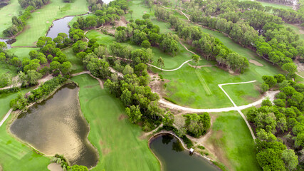Aerial view of golf course at sunset with beautiful trees, pond and sand traps. Scenic panoramic...