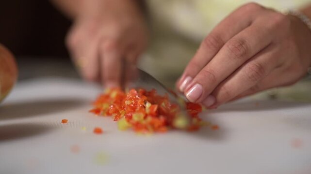 Manos triturando alimentos con cuchillo en la cocina para la cena