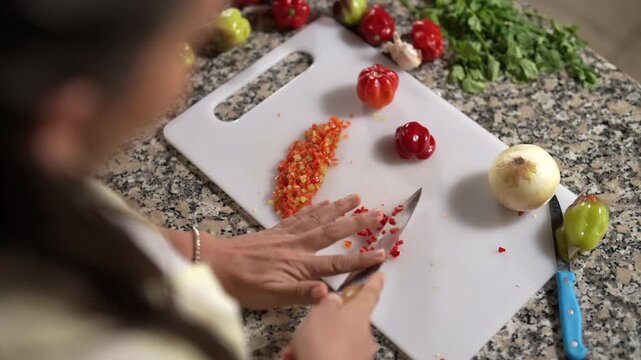 Mujer preparando y cortando alimentos frescos de varios colores en su cocina 
